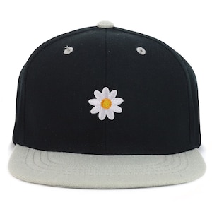 May include: A black and gray baseball cap with a white daisy embroidered on the front.