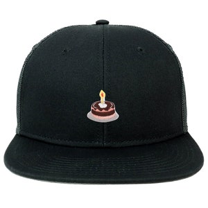 May include: Black trucker hat with a small embroidered patch of a pink and brown birthday cake with a yellow candle on top.