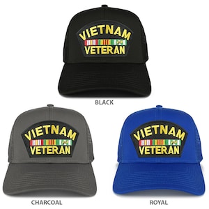 May include: Three trucker hats with a black, charcoal, and royal blue color scheme. Each hat features a yellow embroidered patch that reads "Vietnam Veteran" with a row of colorful ribbons above the text.