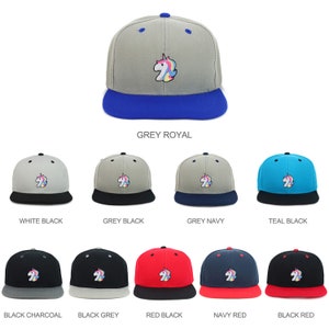 Op de afbeelding: Een verzameling baseballcaps met een eenhoorn-afbeelding in verschillende kleurencombinaties. De caps zijn verkrijgbaar in grijs, wit, teal, zwart, rood en marine.