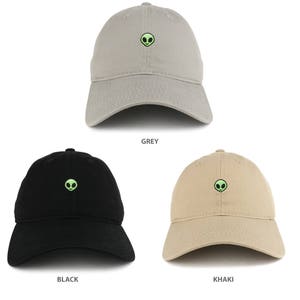 May include: Three baseball caps in different colors: grey, black, and khaki. Each cap features a small green alien face embroidered on the front.
