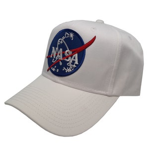 Puede incluir: Gorra de béisbol blanca con un logotipo de la NASA bordado en azul y rojo en la parte delantera.