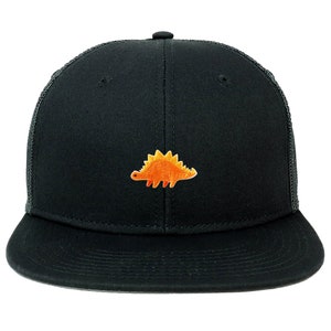 May include: Black trucker hat with a flat brim and a mesh back. The hat features an embroidered orange and yellow stegosaurus dinosaur patch on the front. The hat has a snapback closure.