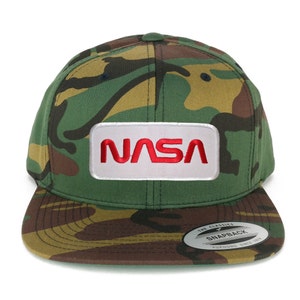 May include: A green, brown, and black camouflage baseball cap with a white patch that says "NASA" in red letters. The cap has a black adjustable strap in the back and a white sticker on the underside of the brim that says "The Classics Snapback Yupoong Since 1974."