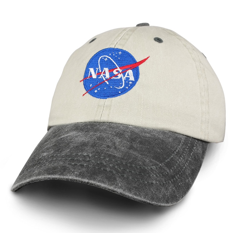 May include: A beige and black baseball cap with a blue and red embroidered NASA logo on the front.
