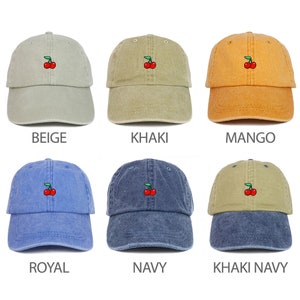 Puede incluir: Seis gorras de béisbol de diferentes colores con una pequeña cereza bordada en la parte delantera. Los colores son beige, caqui, mango, azul real, azul marino y caqui marino.