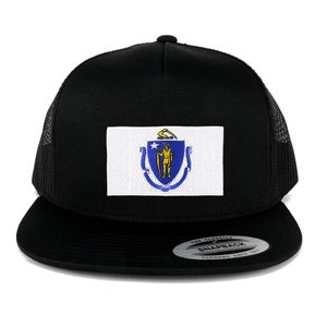 May include: A black trucker hat with a white patch featuring the state seal of Massachusetts. The seal depicts a Native American man standing on a blue shield with a gold star above him. The hat has a black mesh back and a black snap closure with the text "The Classic Snapback Yupoong Since 1975".