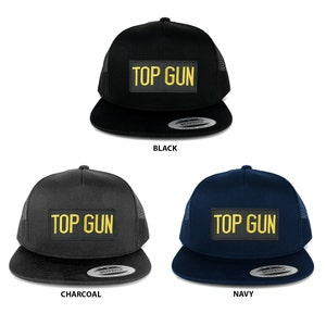 Może przedstawiać: Trzy czapki trucker z siateczką z tyłu w kolorze czarnym i przodem w kolorze czarnym, szarym lub granatowym. Każda czapka ma naszywkę z haftem w kolorze żółtym z napisem "TOP GUN".
