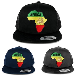 Op de afbeelding: Drie zwarte, donkerblauwe en grijze trucker caps met een groene, gele en rode omtrek van het Afrikaanse continent met het woord "Afrika" in gele letters. De omtrek van Afrika omvat ook een leeuw met een gele manen en een rode kroon.