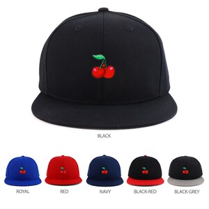 Puede incluir: Una selección de gorras de béisbol con un diseño de cereza. Las gorras están disponibles en negro, azul real, rojo, azul marino, negro con visera roja y negro con visera gris.