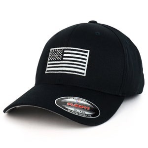 Peut inclure: Casquette de baseball noire avec un drapeau américain brodé en blanc sur le devant. La casquette porte une étiquette Flexfit sur le côté qui indique "The Original Flexfit XL/XXL It Fits Your Life."