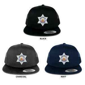 May include: Three trucker caps in black, charcoal, and navy blue. Each cap has a mesh back and a flat peak. The front of each cap displays a security officer badge with the words "SECURITY OFFICER".