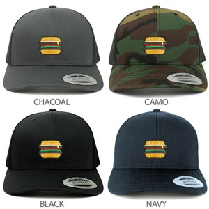Pode incluir: Quatro bonés de caminhoneiro em diferentes cores: carvão, camuflagem, preto e azul marinho. Cada boné apresenta uma imagem bordada de um hambúrguer com alface, tomate e queijo.