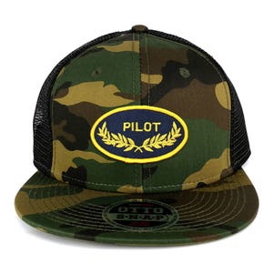 May include: Camouflage trucker hat with a black mesh back. The hat has a navy blue oval patch with a yellow border and the word "PILOT" in yellow letters. The patch has two gold laurel wreaths around it.