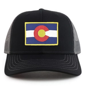 Puede incluir: Una gorra de camionero negra y gris con un parche de la bandera del estado de Colorado. El parche presenta un círculo amarillo con una 'C' roja en su interior, rodeado de un círculo azul y rayas blancas.