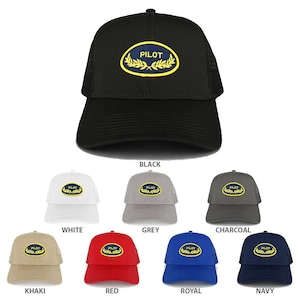 May include: A selection of trucker caps in various colours, including black, white, grey, khaki, red, royal blue, and navy. Each cap has a mesh back and a curved peak. The front displays a patch with the word "PILOT" in white, surrounded by a gold laurel wreath.