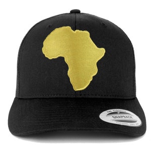 Könnte beinhalten: Schwarze Trucker-Kappe mit einem goldenen, gestickten Umriss des afrikanischen Kontinents. Die Kappe hat ein schwarzes Netzrücken und ein schwarzes Frontpanel mit einem weißen "The Classics" Label und dem Text "Snapback".