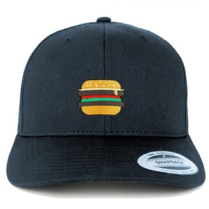 May include: A black trucker hat with a yellow, red, and green embroidered hamburger on the front. The hat has a black mesh back and a black adjustable strap with a "The Classic Snapback" label.