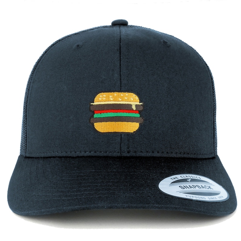 May include: A black trucker hat with a yellow, red, and green embroidered hamburger on the front. The hat has a black mesh back and a black adjustable strap with a "The Classic Snapback" label.