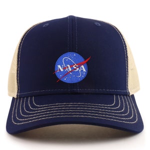 Puede incluir: Una gorra de camionero azul marino y beige con un logotipo de la NASA azul bordado en la parte delantera.