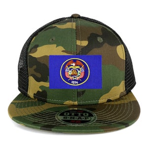 Puede incluir: Una gorra de camionero de camuflaje con una malla negra en la parte posterior. La parte delantera de la gorra presenta un parche de la bandera del estado de Utah con el sello y el año 1896.