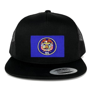 Puede incluir: Gorra de camionero negra con un parche bordado azul y amarillo de la bandera del estado de Utah. El parche presenta el sello del estado con un águila, una colmena y el año 1896. La gorra tiene una parte trasera de malla negra y un cierre de presión negro.