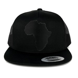 May include: Black trucker hat with a black outline of the continent of Africa on the front. The hat has a black mesh back and a black snap closure. The hat is made by Yupoong and is labeled "The Classic Snapback Since 1975."