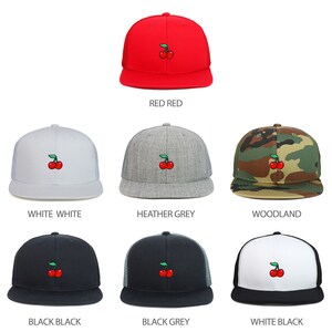 Puede incluir: Seis variaciones de color diferentes de una gorra de camionero con una cereza roja bordada en la parte delantera. Las gorras están disponibles en rojo, blanco, gris jaspeado, camuflaje de bosque, negro y negro con una malla gris en la parte posterior.