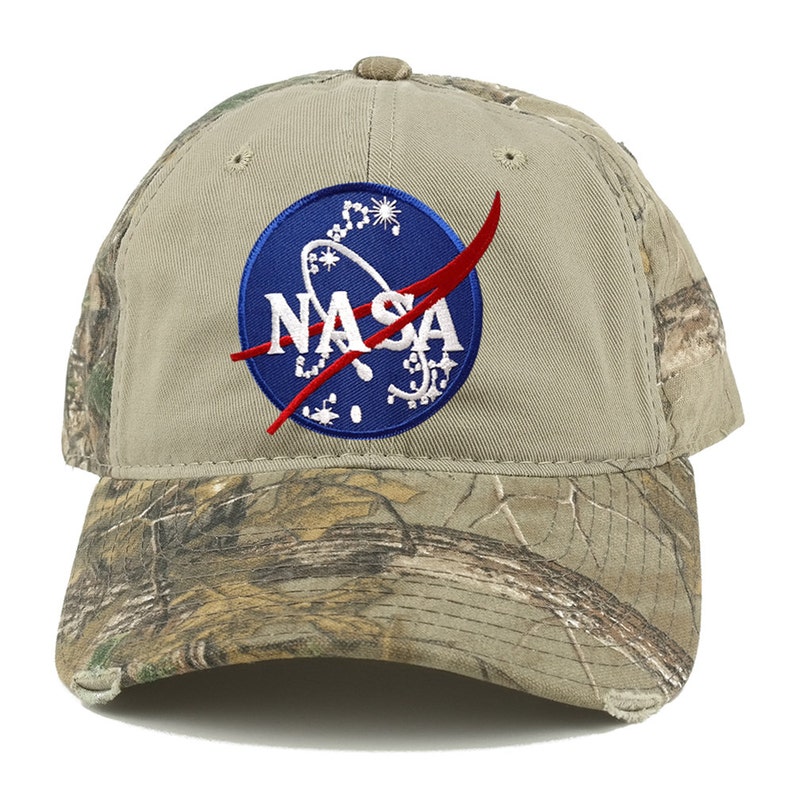 May include: A tan baseball cap with a camouflage brim. The front of the cap features a blue and red embroidered NASA logo.