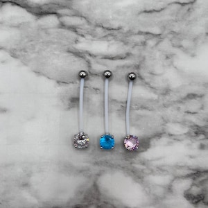 May include: Three silver belly button rings with clear, blue, and pink gem stones.