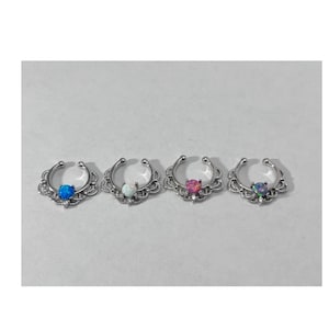 May include: Four silver nose rings with different colored opal stones. The rings are in a row on a white surface. The stones are blue, white, pink, and green.