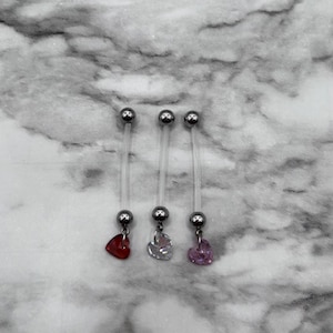 May include: Three clear body jewelry pieces with silver balls on each end and a dangling heart charm. The hearts are red, clear, and pink.
