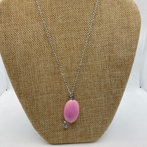 May include: A silver chain necklace with a pink oval pendant.