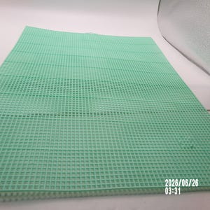 May include: A rectangular mint green plastic canvas sheet featuring a uniform grid of small square holes throughout its surface. The material is rigid and flat, designed for needlepoint or craft projects, with the date 2026/06/26 03:31 printed in white.