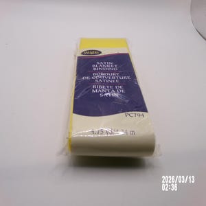 May include: A package of Wrights satin blanket binding. The binding is yellow and white, with a blue and white label that reads "SATIN BLANKET BINDING" in English, French, and Spanish. The package contains 4.75 yards (4.34 m) of binding.
