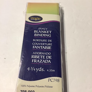 May include: A package of Wrights Fancy Blanket Binding. The package is wrapped in clear plastic and features text in English, French, and Spanish. The binding is 4 3/4 yards (4.35m) long and is multi-rainbow colored.