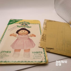 May include: A See & Sew 5422 sewing pattern envelope for Cabbage Patch Kids clothes featuring an illustration of a doll in a pink striped jumper. The envelope includes printed text and a separate tan paper pattern sheet labeled Jumper.