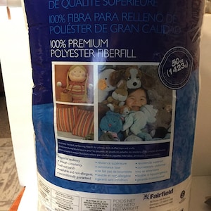 May include: A large bag of Poly-Fil 100% Premium Polyester Fiberfill, ideal for pillows, dolls, and crafts. The bag is dark blue with white text and a picture of a doll and stuffed animals. The net weight is 50 oz (1423g).