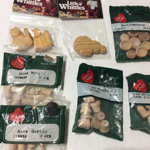 May include: Assortment of small, unfinished wooden craft parts, including wine bottles, bowls, and flower pots. Packaged in clear plastic bags with labels from "Lara's Crafts" and "Little Whittles". Ideal for miniature projects.