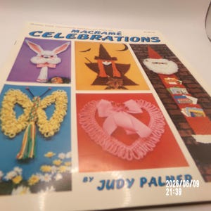 May include: A softcover craft book titled Macramé Celebrations by Judy Palmer. The cover features five colorful photographs of macramé projects including a white rabbit, a witch, a Santa Claus wall hanging, a yellow butterfly, and a pink heart.