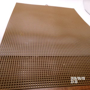 May include: A rectangular brown plastic canvas sheet featuring a uniform grid of small square holes throughout its surface. The material is rigid and flat, designed for needlepoint or crafting projects. The date 2026/06/05 23:35 is printed in white.
