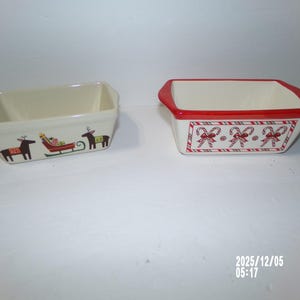 May include: Two rectangular ceramic baking dishes. One is off-white with a reindeer and sleigh design. The other is white with a red rim and a candy cane and bow pattern. Both are holiday-themed.