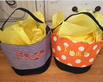 May include: Two Halloween trick-or-treating bags with personalized names. One bag is purple and white striped with the name "Paige" embroidered on it. The other bag is orange with white polka dots and the name "Taylor" embroidered on it.