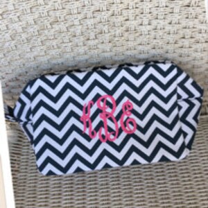 May include: Black and white chevron patterned zippered makeup bag with a pink monogram "KBE" embroidered on the front.