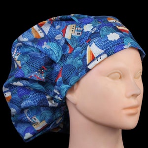 May include: Blue surgical scrub hat with a pattern of white waves and red, orange, and yellow sailboats.