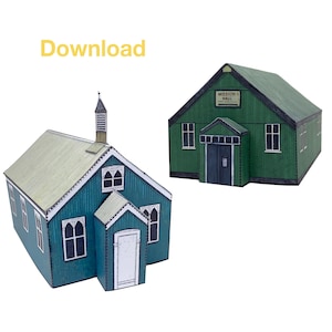 Op de afbeelding: Twee papieren modelgebouwen, een kerk met een toren en een missiehuis. Beide gebouwen zijn groen met witte versieringen en ramen.