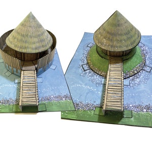 以下が含まれることがあります： 丸い茅葺き屋根の小屋のペーパークラフトモデル。小屋には木製の歩道があり、入り口につながっています。小屋は石の壁で囲まれており、青い水盤の上に緑の草と石が置かれています。