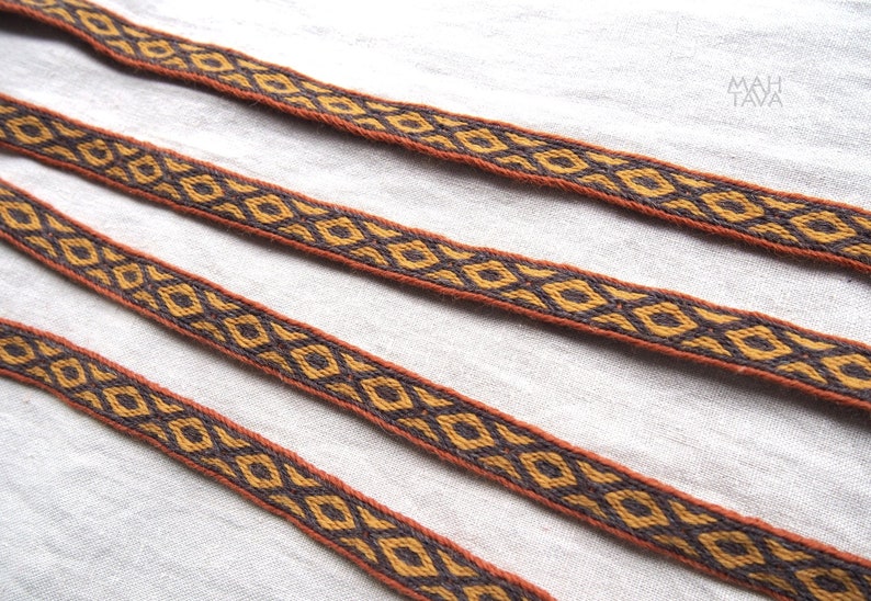 May include: Three brown and gold woven ribbon trims with a geometric diamond pattern.