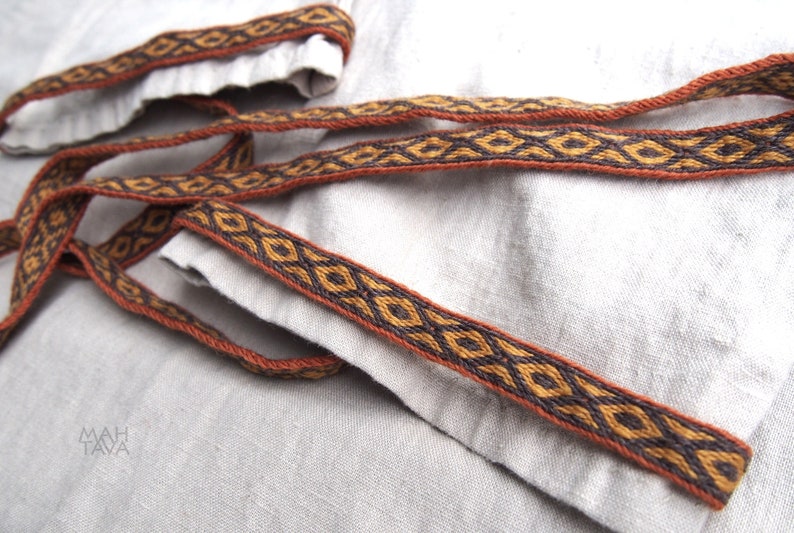 May include: Close-up of a brown and black woven trim with a diamond pattern. The trim is on a light gray fabric.