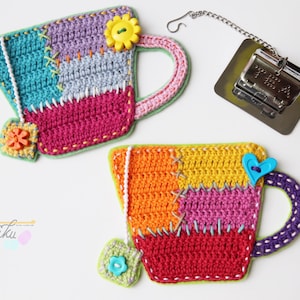 May include: Two crocheted teacup coasters with colorful patchwork designs. One coaster features a blue, pink, and green design with a yellow flower button. The other coaster features a red, orange, yellow, and pink design with a blue heart button.